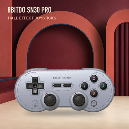 Gray 8BitDo SN30 Pro Hall Effect controller against a red retro studio backdrop.