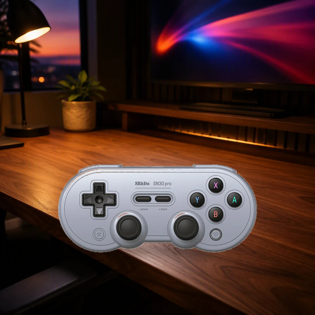 Gray 8BitDo SN30 Pro Hall Effect controller on a wooden gaming desk beside a softly lit monitor.